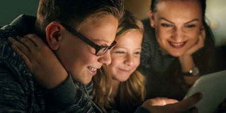 To børn og en kvinde kigger på en skærm