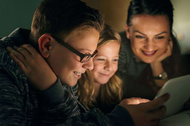 To børn og en kvinde kigger på en skærm